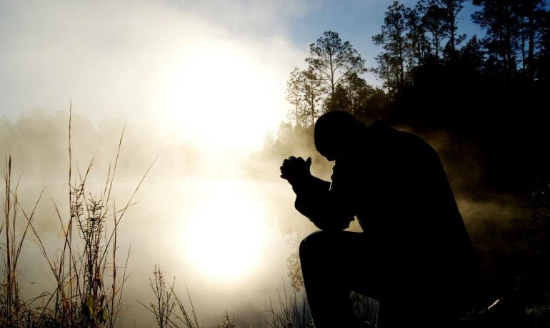 Man sat in prayer in the morning sun